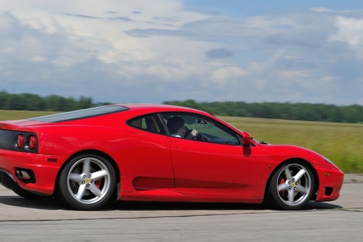 Czerwone Ferrari w tle pola i las